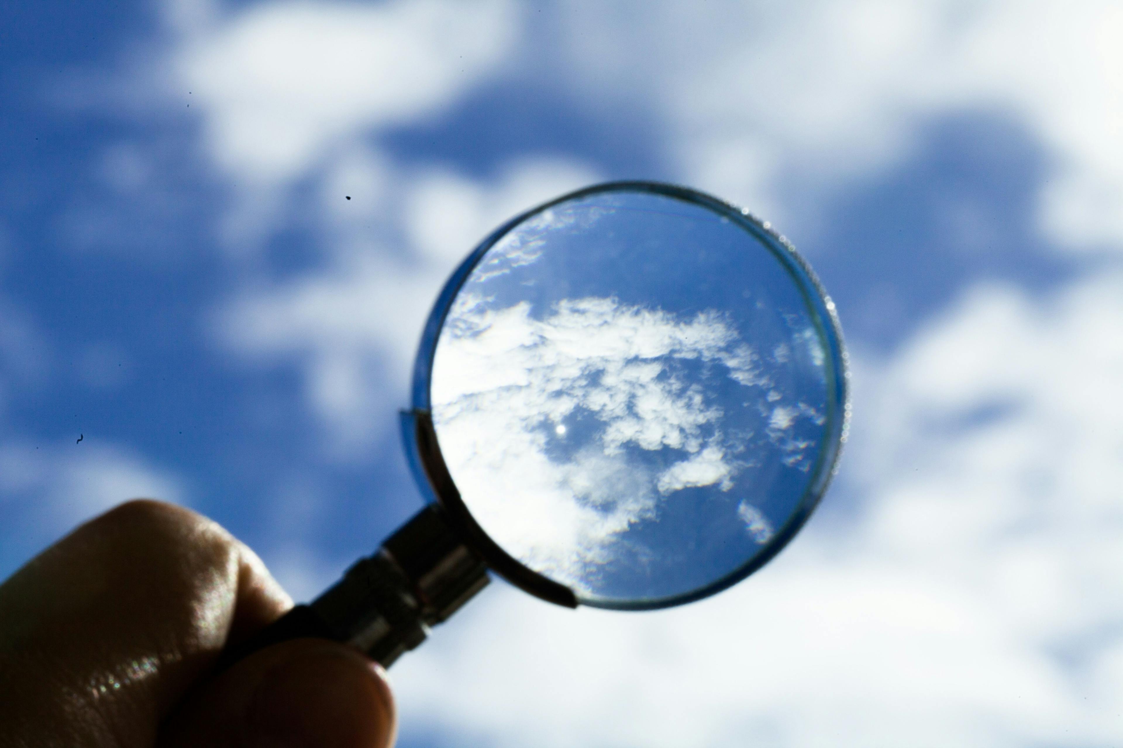magnifying glass held up to sky for clear vision of clouds