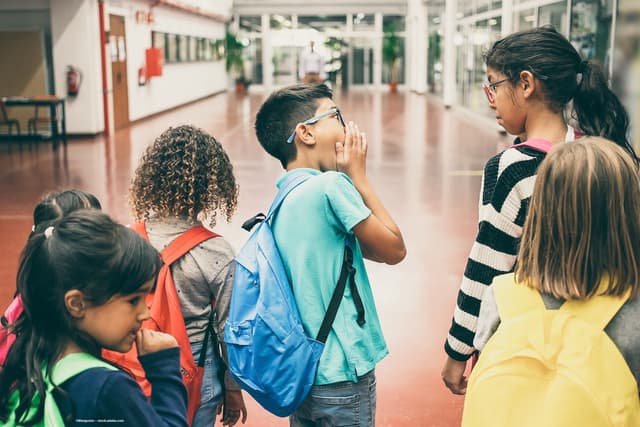 A group of children. A boy and a girl at the front, both wearing glasses, look at each other. Image credit: ©Mangostar – stock.adobe.com