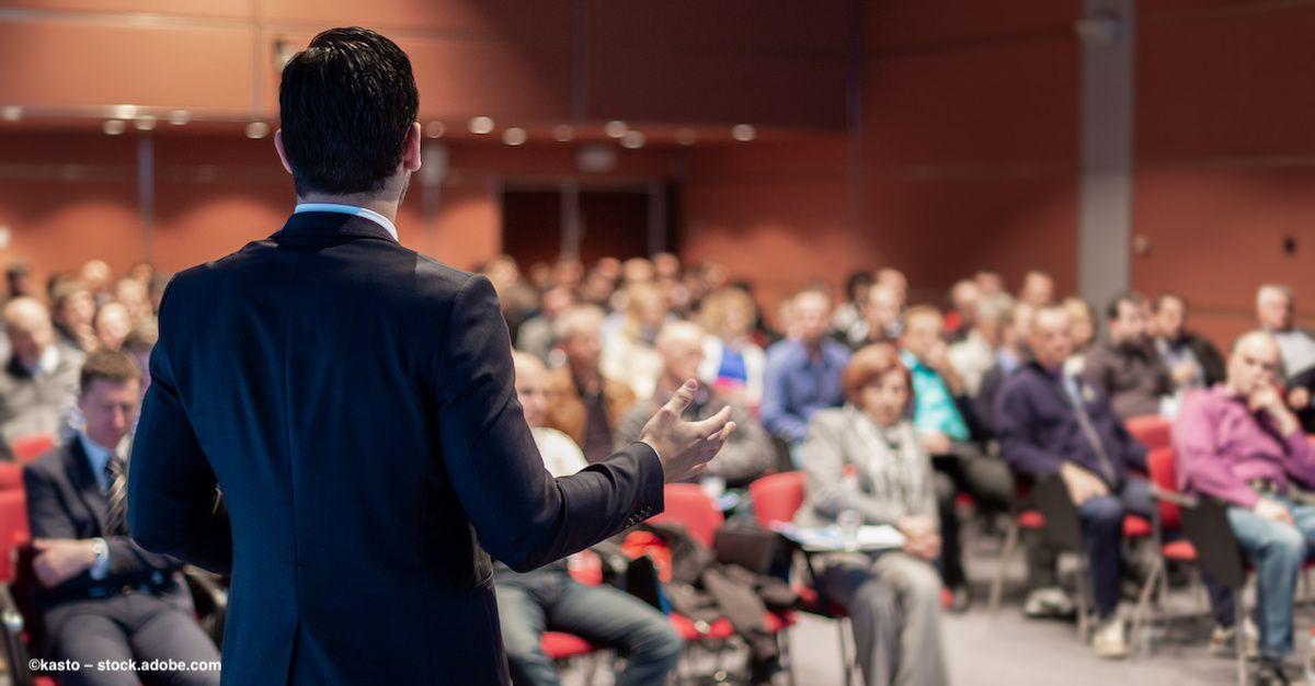 An audience watches a business person make a presentation at a conference. Image credit: ©kasto – stock.adobe.com