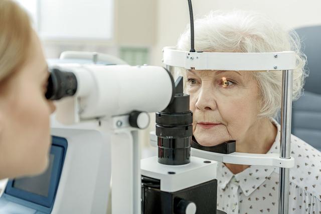 An ophthalmologist conducts an exam on an elderly female patient. Image credit: ©Yakobchuk Olena – stock.adobe.com