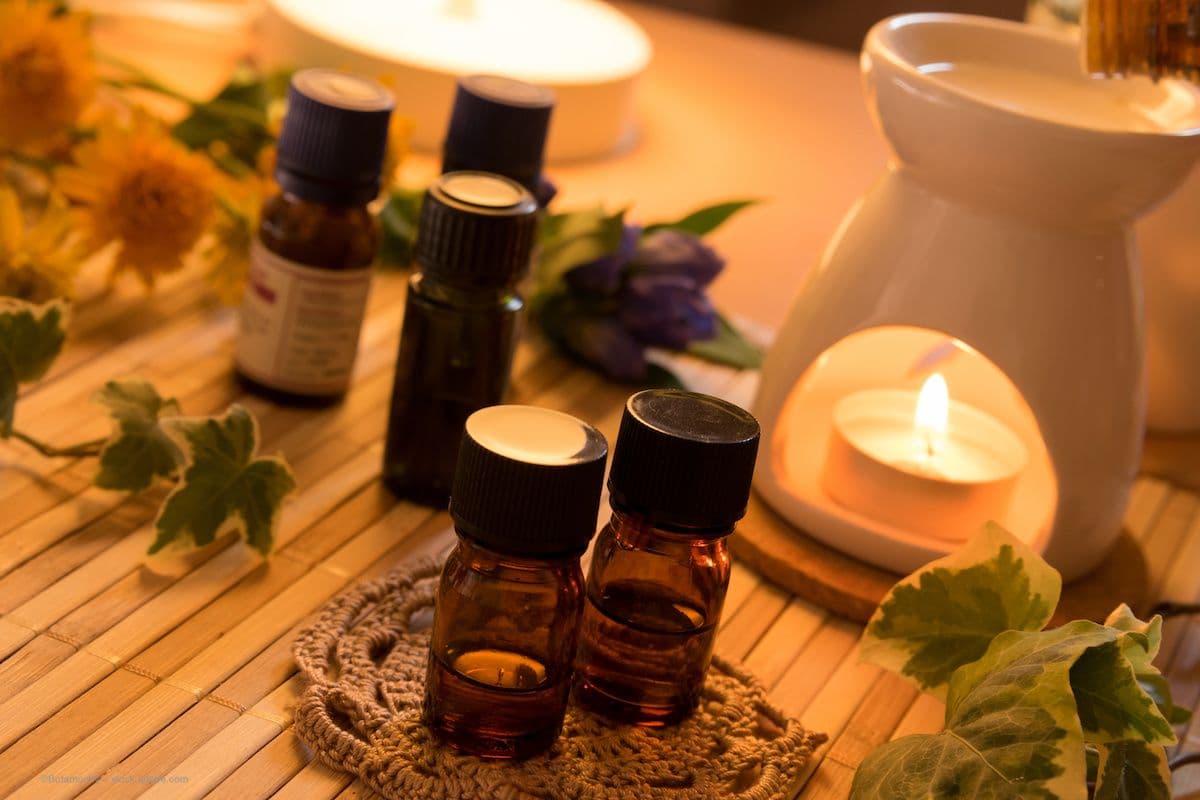 Bottles of essential oils are placed next to an essential oil aromatherapy diffuser in a calm, warm, spa-like environment. Image credit: ©Botamochy – stock.adobe.com