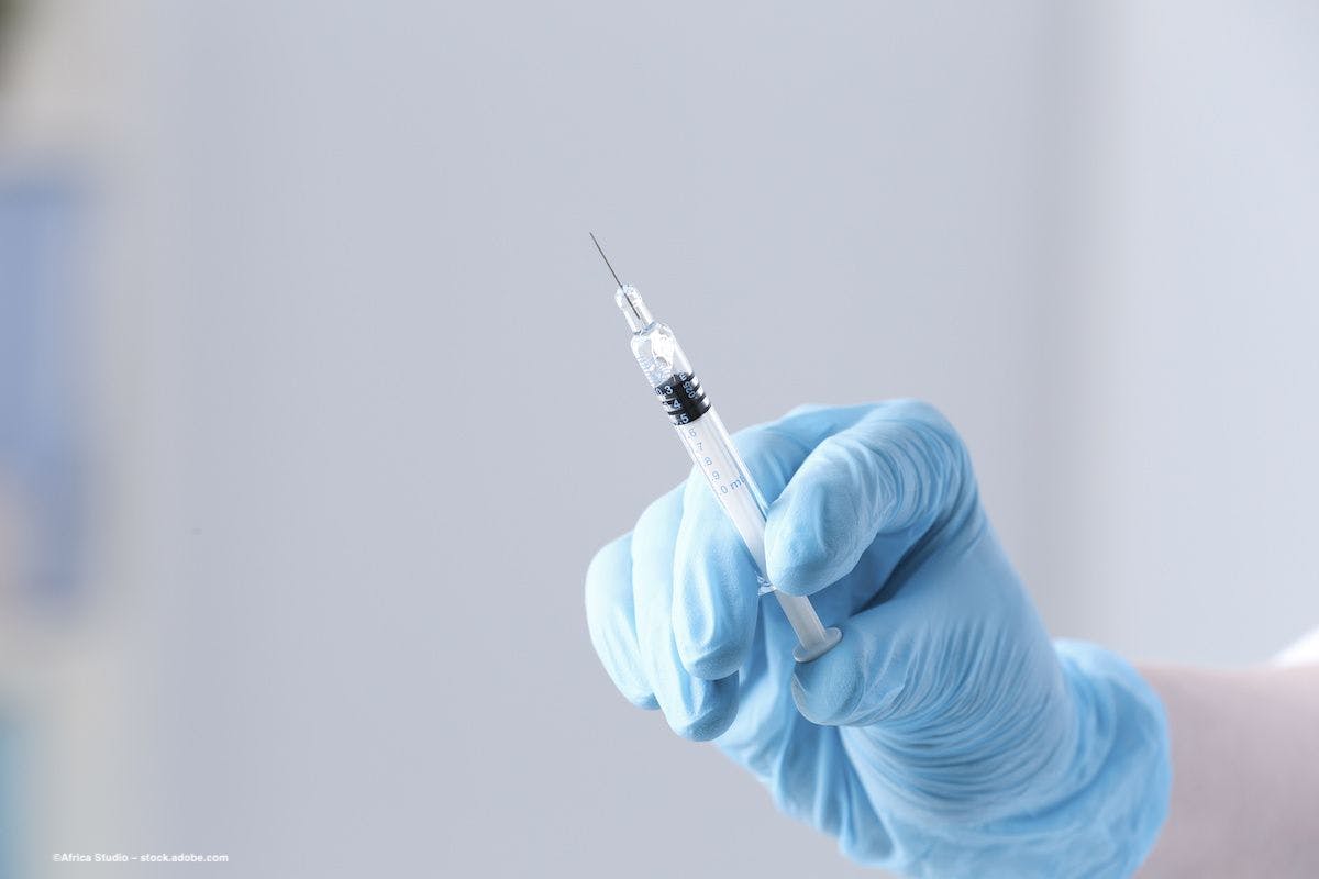 A clinician's gloved hand holds a syringe full of liquid. Image credit: ©Africa Studio – stock.adobe.com