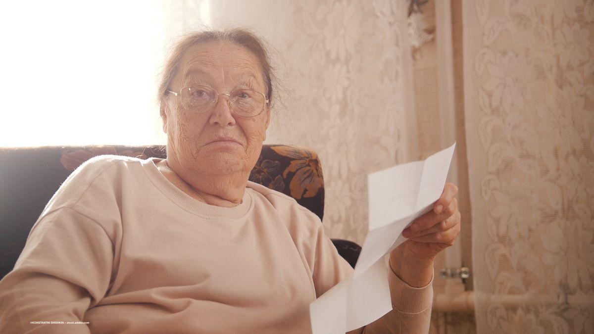 A woman with glasses looks at the camera. She has a sheet of paper in her hand. Image credit: ©KONSTANTIN SHISHKIN – stock.adobe.com