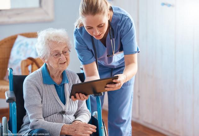 A healthcare professional helps an older female patient with glasses read a chart. Image credit: ©David L/peopleimages.com – stock.adobe.com