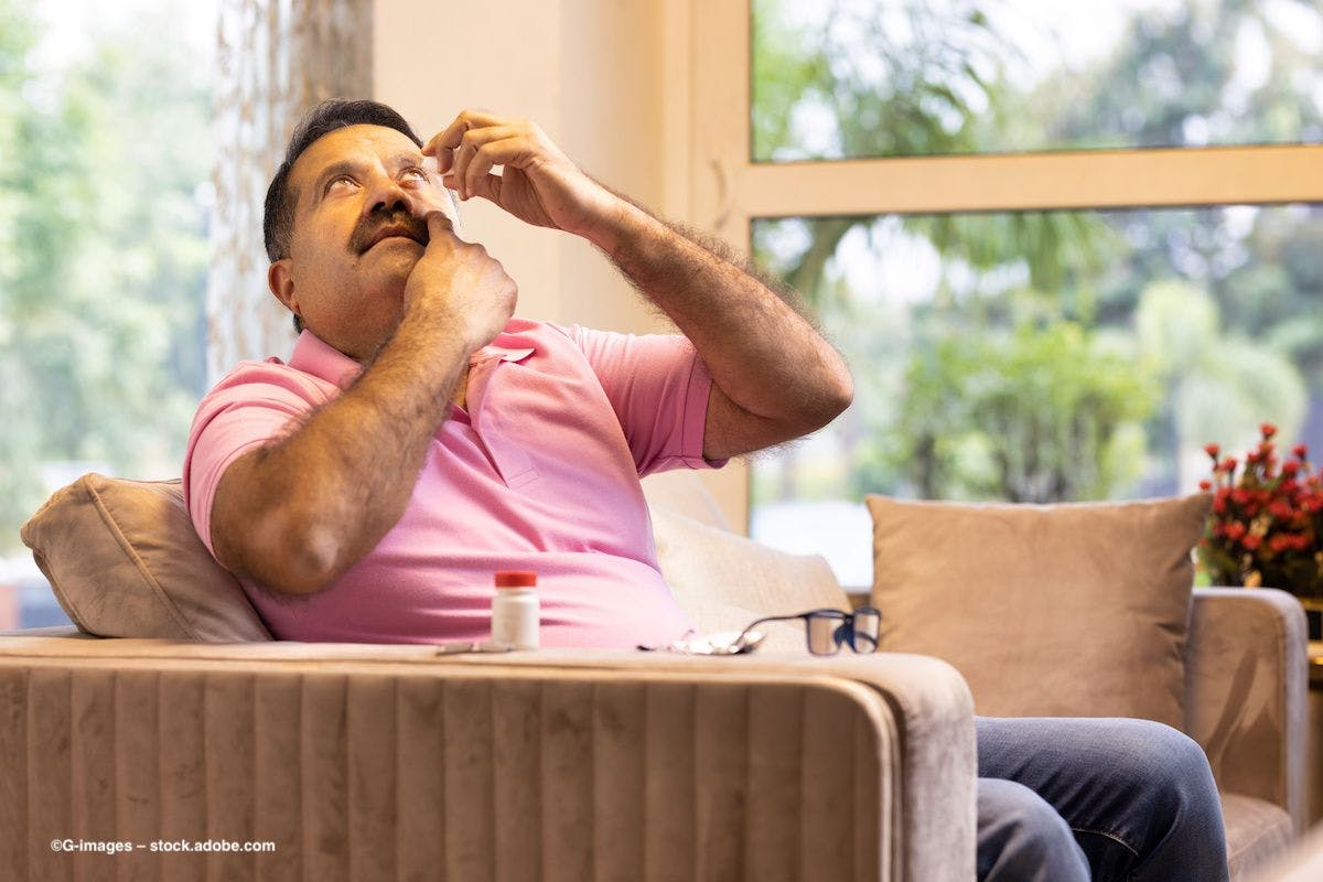 A man in a chair administers an eye drop to himself. Image credit: ©G-images – stock.adobe.com