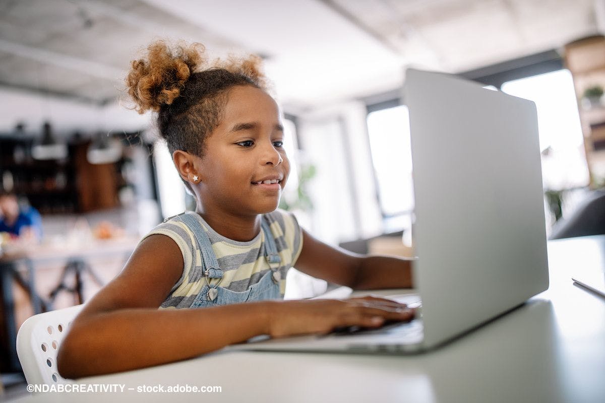 A child sits in front of a laptop computer, looking at the screen. Image credit: ©NDABCREATIVITY – stock.adobe.com