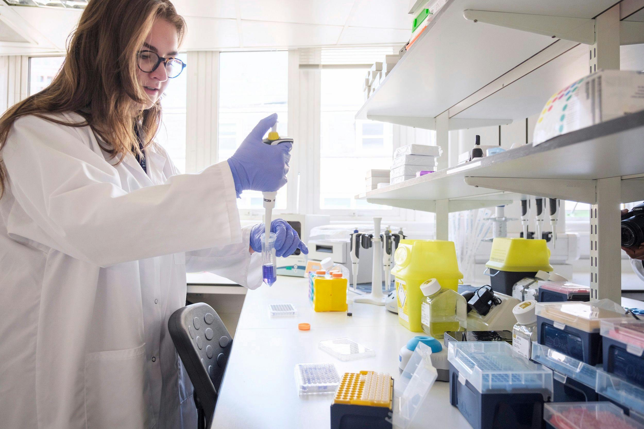A researcher in a white coat performs work in a lab. Image courtesy Moorfields Eye Charity.