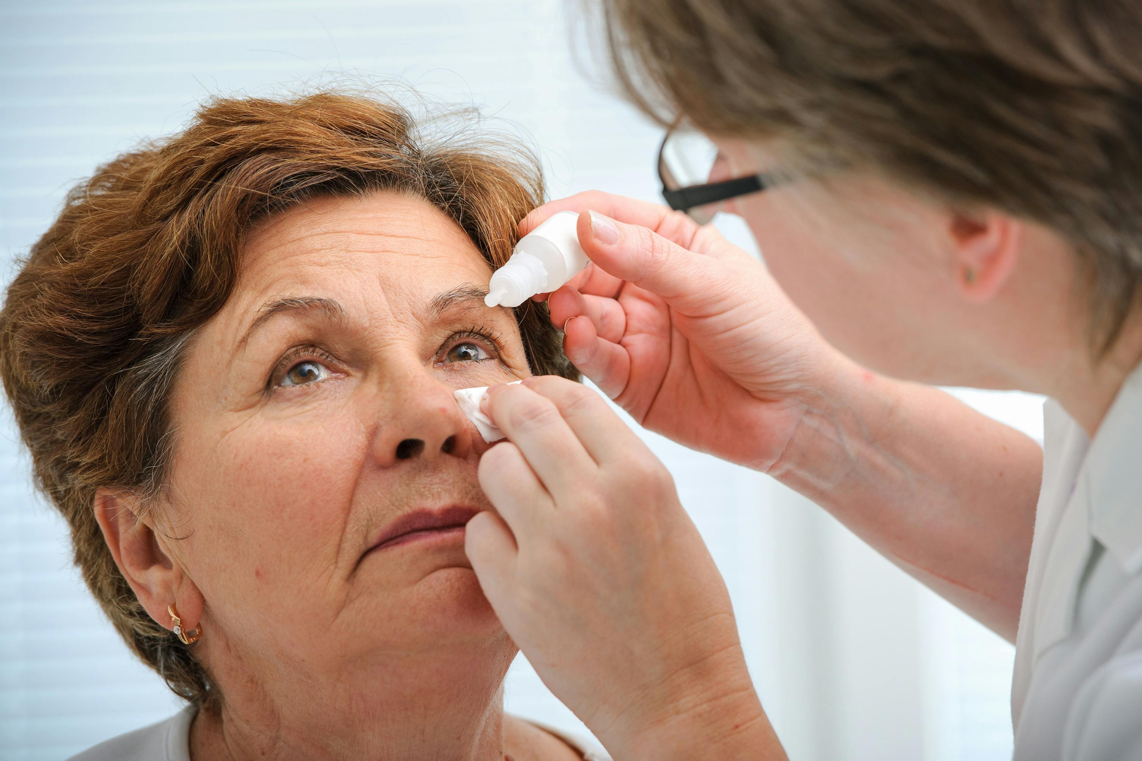 Eye care professional administering eye drops to woman
