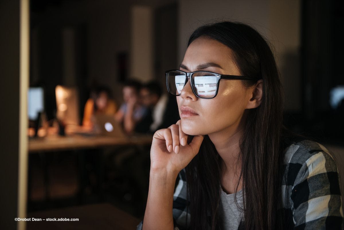 A woman with glasses sits at a computer in the dark. Image credit: ©Drobot Dean – stock.adobe.com