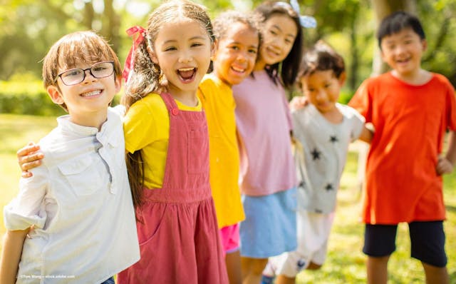 A group of children standing outdoors. One wears glasses. Image credit: ©Tom Wang – stock.adobe.com