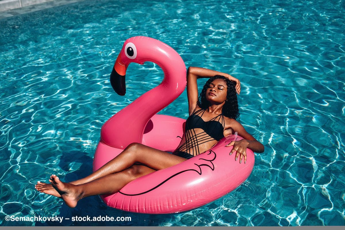 A woman in sunglasses sits in a pool float shaped like a flamingo. Photo credit: ©Semachkovsky – stock.adobe.com